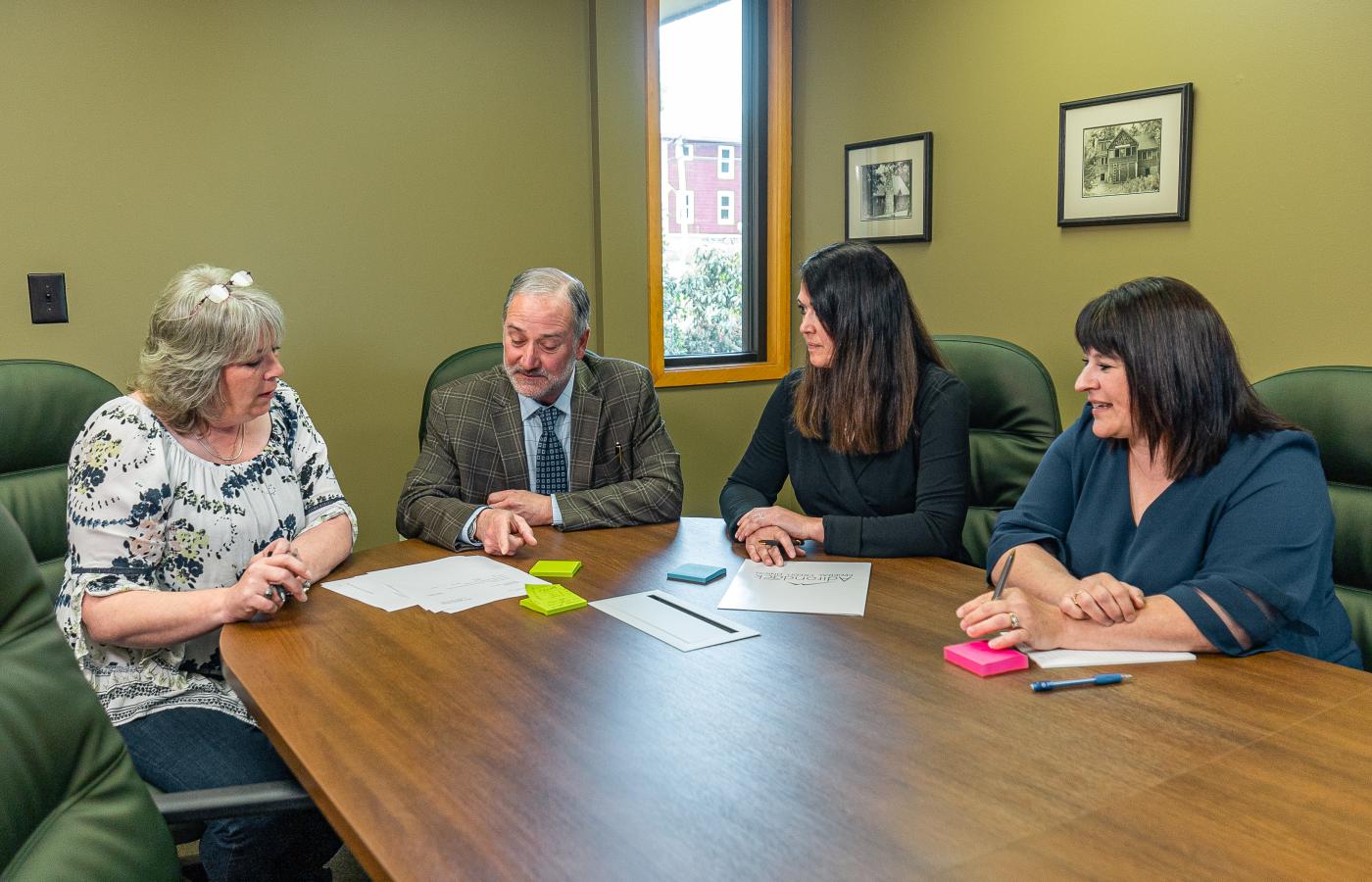 Russ Cronin, CEO and President of Adirondack Regional Federal Credit Union in the Tupper Lake branch meeting room with other staff reviewing paperwork