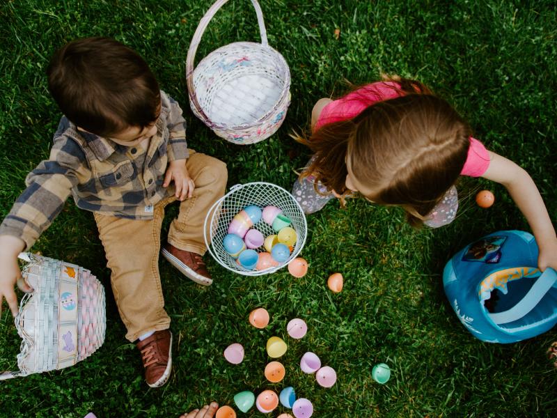 Children sitting on grass with their Easter baskets and eggs after a community Easter egg hunt
