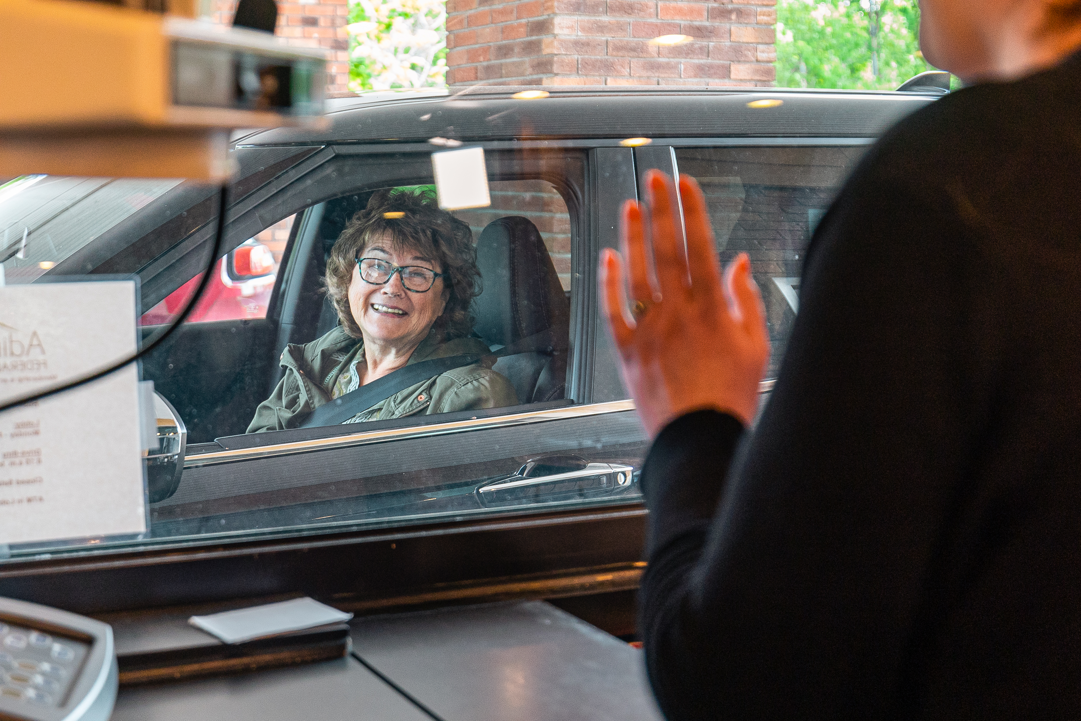 woman in her car happily using the drive thru banking services at the Plattsburgh Branch of Adirondack Regional Federal Credit Union