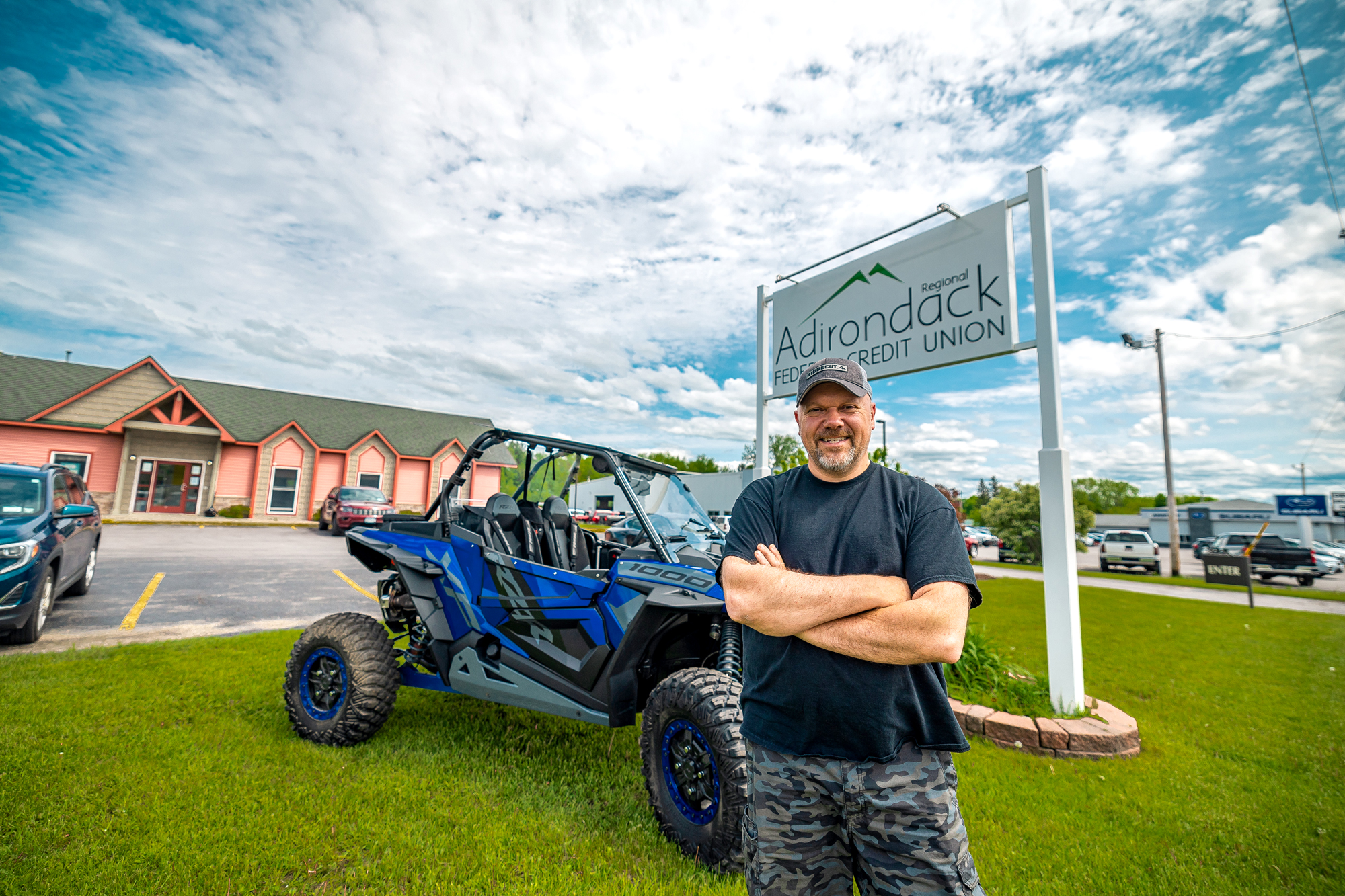 man standing in front of the Adirondack Regional Federal Credit Union sign with a recreational vehicle he bought with a ATV loan from the credit union