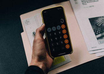 Hand holding calculator over open file folder