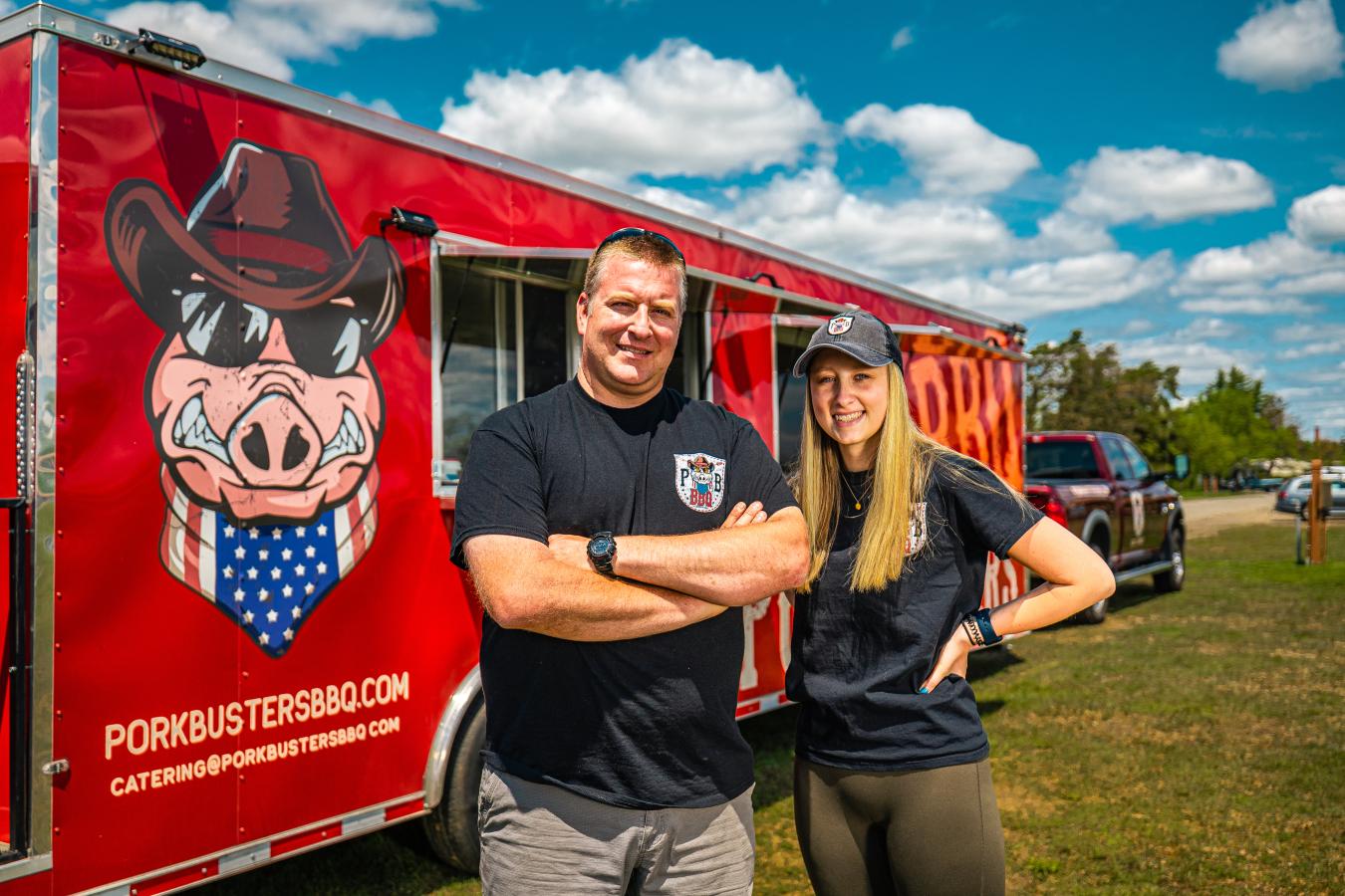 two people standing in front of a BBQ food truck