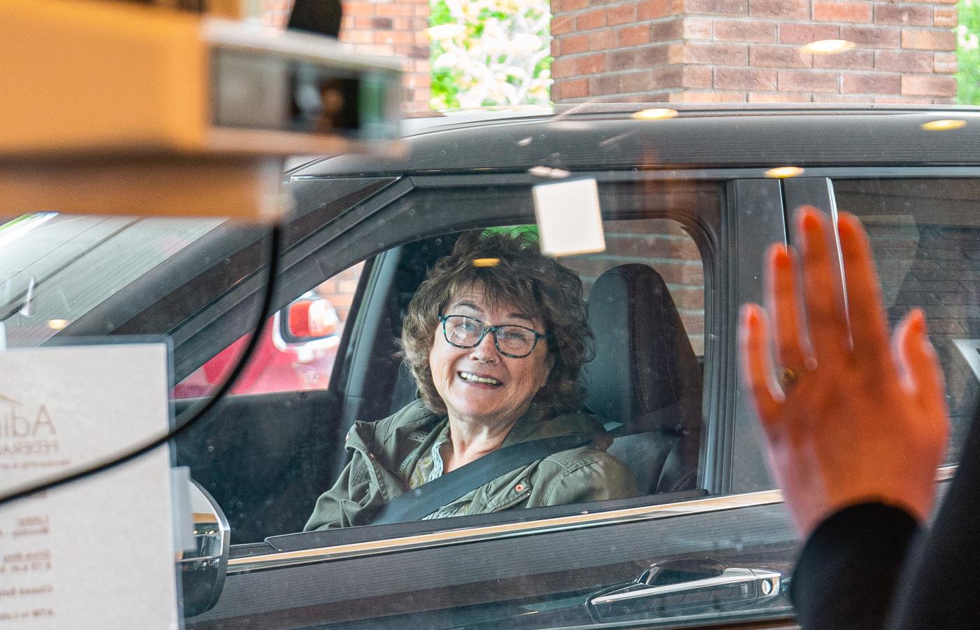 woman in her car happily using the drive thru banking services at the Plattsburgh Branch of Adirondack Regional Federal Credit Union