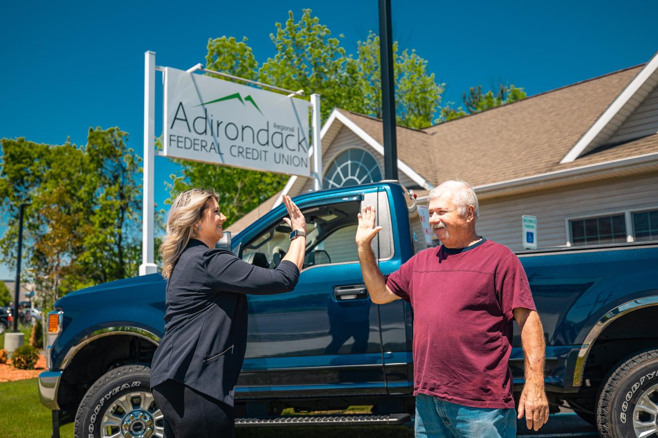 Adirondack Regional FCU manager high-fiving a happy loan member outside of the Tupper Lake Branch