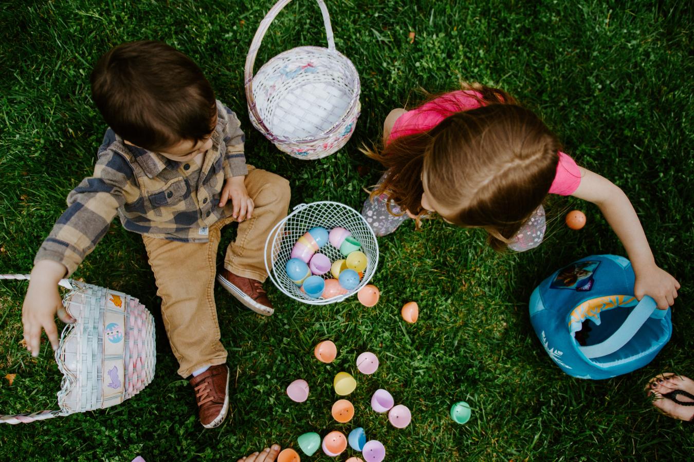 Children sitting on grass with their Easter baskets and eggs.