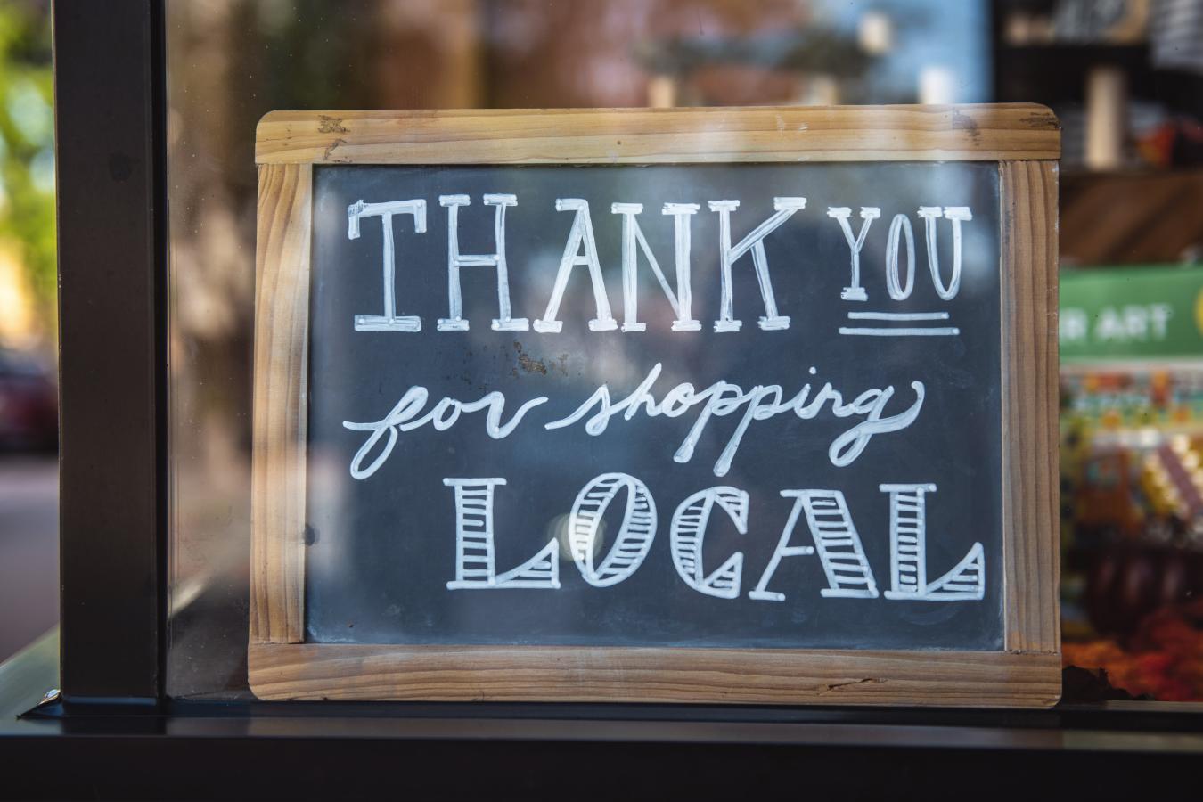 A "thank you for shopping local" chalkboard sign.