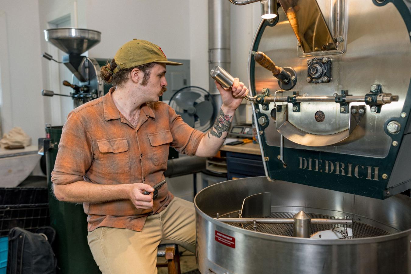 Man operating coffee bean roasting equipment