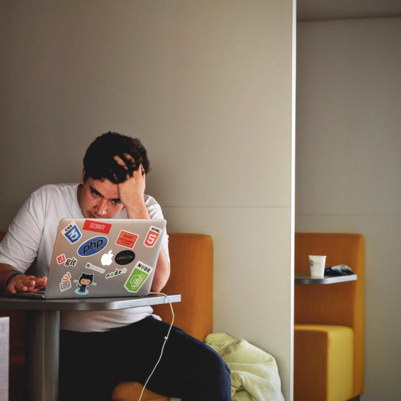 man sitting on his computer looking extremely frustrated and defeated