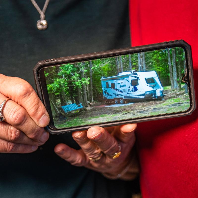 Woman holding a phone with a photo of her new camper she got with a loan from Adirondack Regional Federal Credit Union