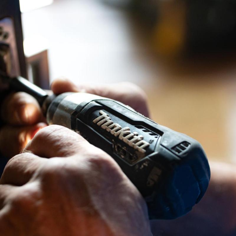 A close up of someone using a power drill to fix door lock